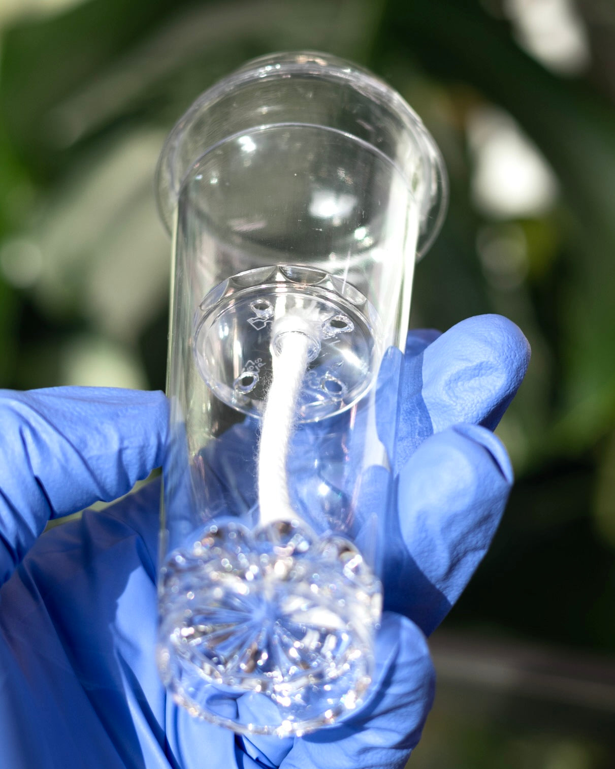 Close-up of empty Pro self-watering cup held in hand, clearly showing the wick hanging from the inner pot into the reservoir
